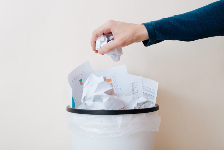 Dłoń wyrzucająca zgnieciony papier do kosza