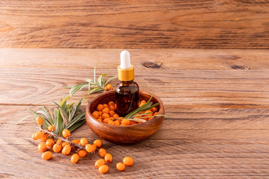 Buteleczka olejku i owoce rokitnika na stole